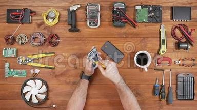 人修手机.. 检查设备内部的部件。 木桌顶景..